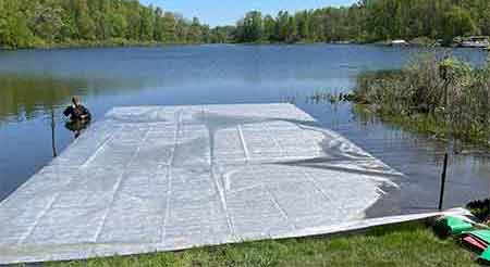 Geotextile for firm lake bottom being installed for muck mitigation.