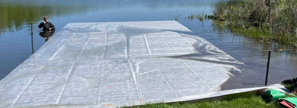 crew member pulling out the custom made muck mat to place on the lake bottom prior to sand stabilization of the beach.