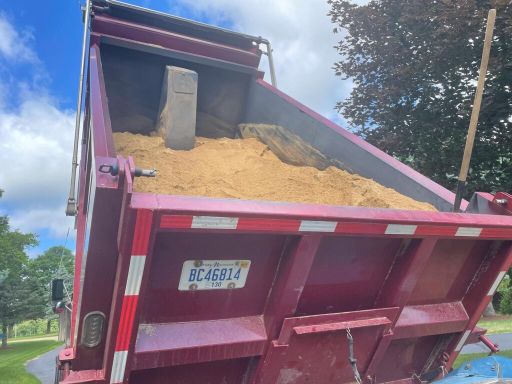 A load of beach sand being delivered for either lake bottom muck removal and mitigation or land side beach installation.