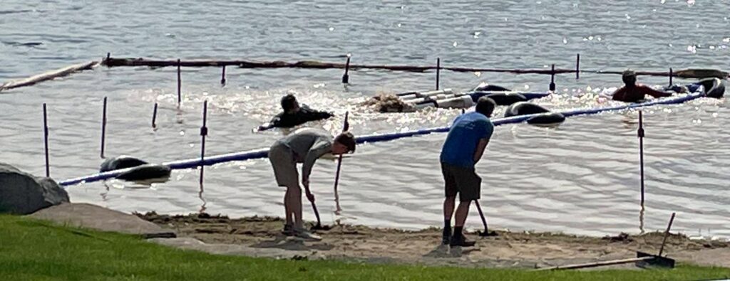 crew working to mitigate muck and sand a beach.