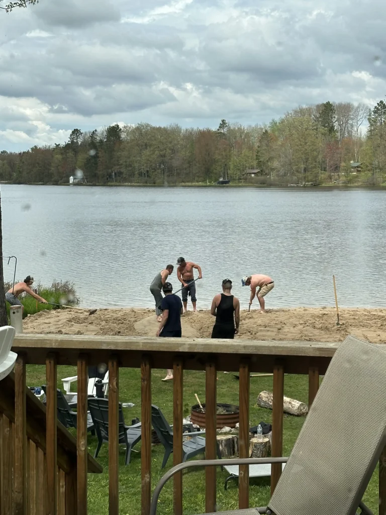 spreading sand evenly with friends helping a DIY beach installation.