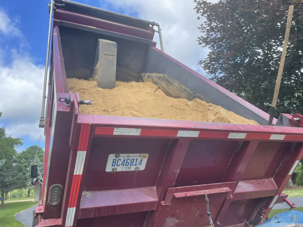 dump truck load of beach sand raising up in preparation to dump.